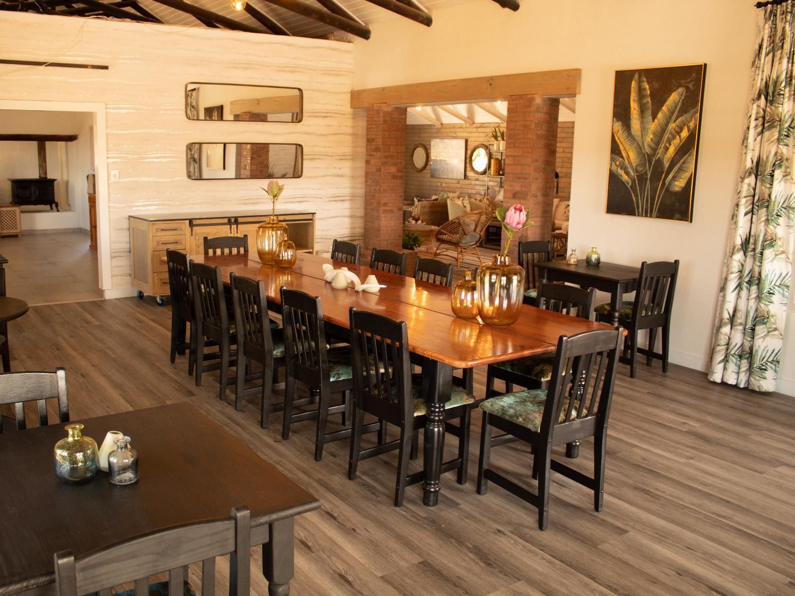 Un espace repas avec une longue table en bois, des chaises noires et des vases décoratifs.