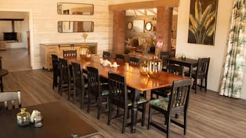 Uma sala de jantar com uma longa mesa de madeira, cadeiras pretas e vasos decorativos.