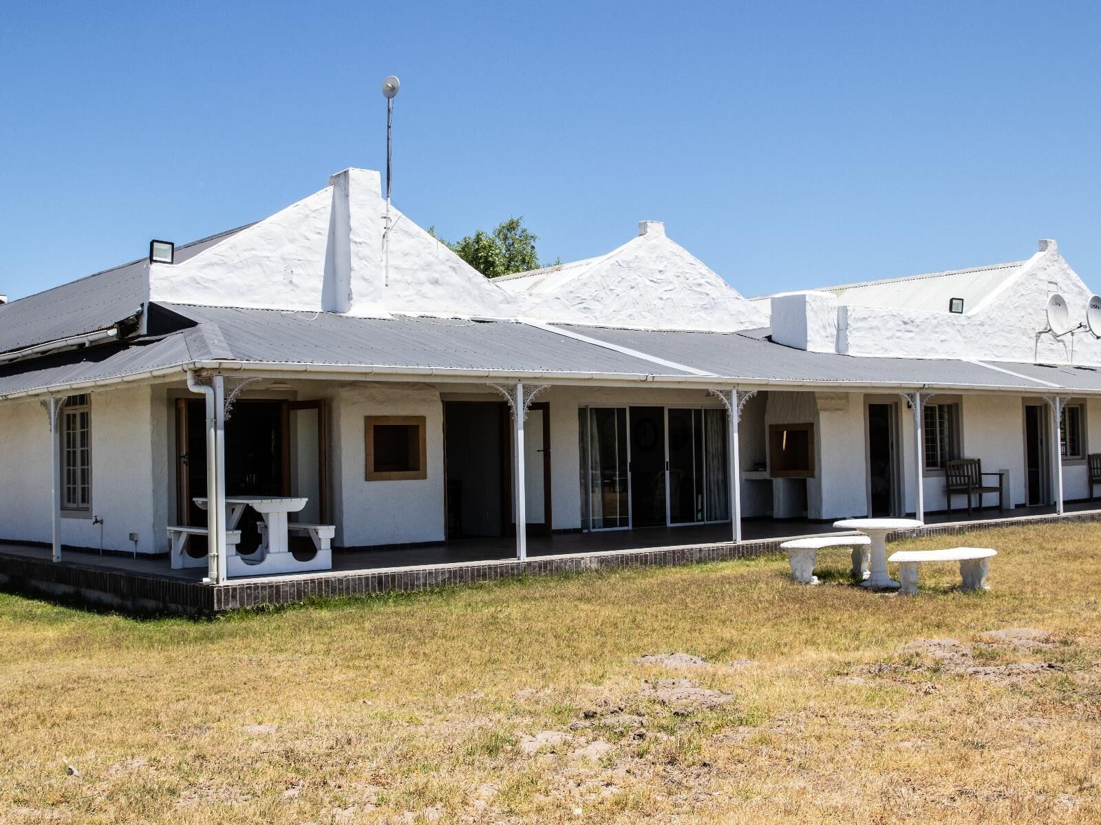 A white building with a covered porch and a satellite dish.