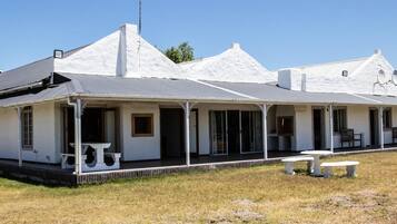 A white building with a covered porch and a satellite dish.