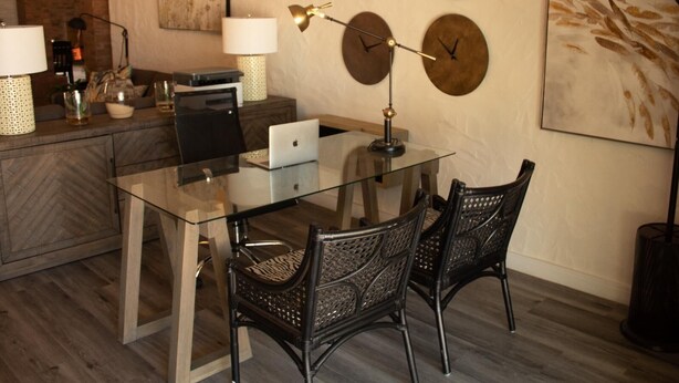 A modern dining area with a glass table, black woven chairs, and decorative wall clocks. - Vyge Valley Estate (Cape Town)
