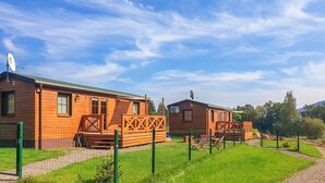 A row of wooden cabins with a fenced yard, satellite dishes, and a clear sky.