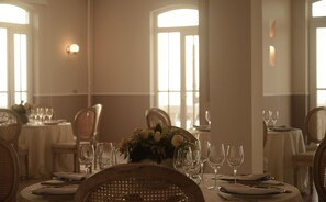A dining table set for a meal with chairs, wine glasses, and a centerpiece of flowers. - Ermita Cartagena, A Tribute Portfolio Hotel (Cartagena)
