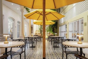 A hotel lobby with round tables, yellow umbrellas, and a tiled floor. - Ermita Cartagena, A Tribute Portfolio Hotel (Cartagena)