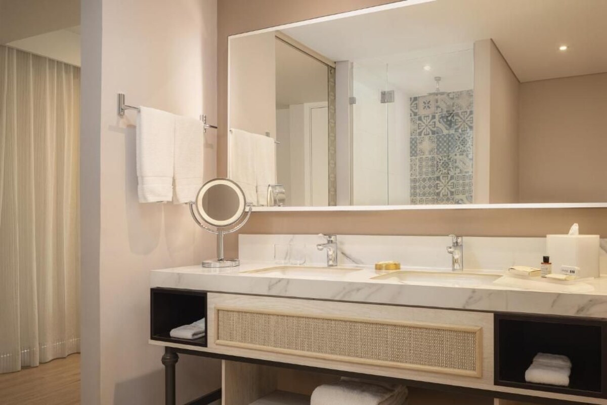 Un baño moderno con un espejo grande, un lavabo y un mueble de baño con estantes.