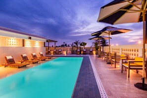 A swimming pool with lounge chairs and umbrellas, surrounded by walls with circular patterns and palm trees. - Ermita Cartagena, A Tribute Portfolio Hotel (Cartagena)