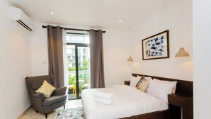 Een hotelkamer met een bed, een stoel, een nachtkastje en een raam met gordijnen.