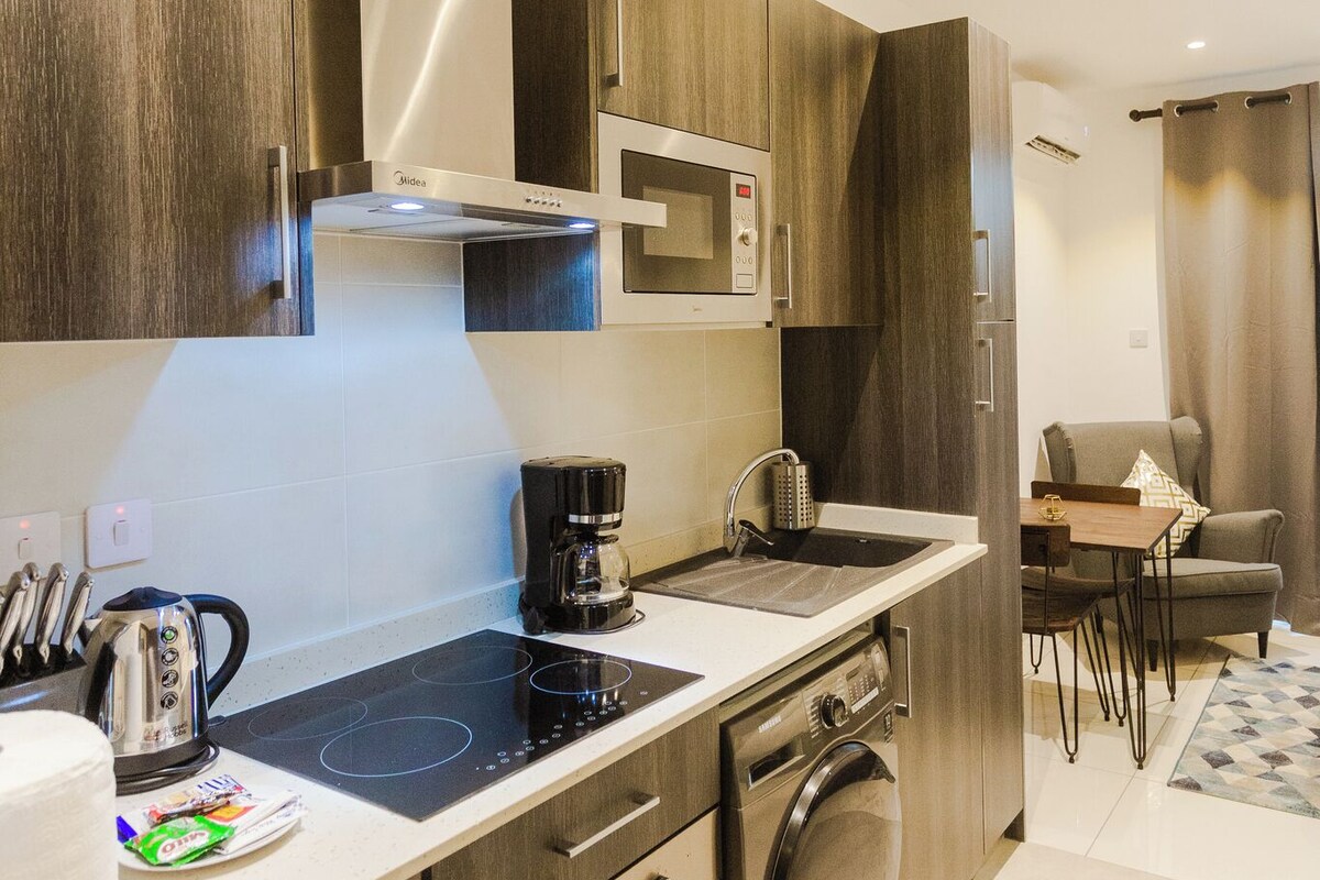 A modern kitchen with a built-in microwave, stove, and oven, a coffee maker, and a dining area with a table and chairs.