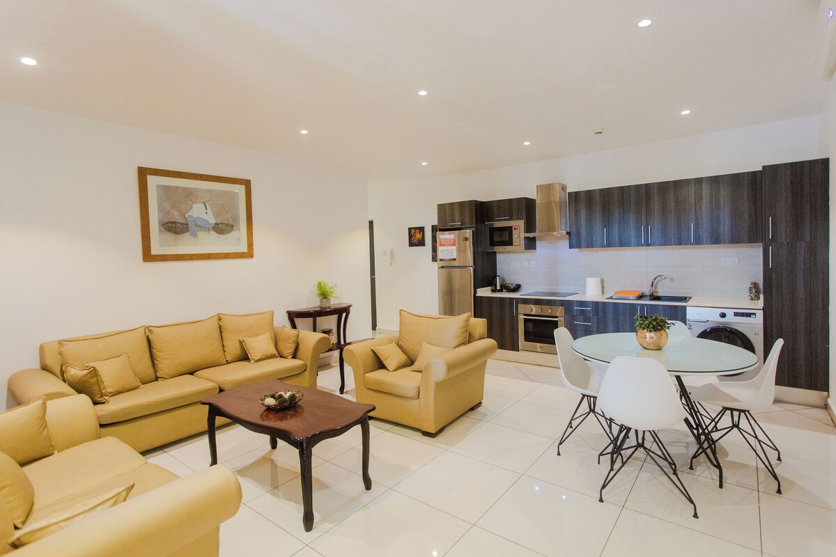A modern living room with a sofa set, a coffee table, and a dining area with a glass table and chairs.