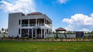 A modern building with a flat roof, large windows, and a covered outdoor area.