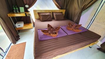 A bed with a brown headboard, two pillows, and a purple blanket.