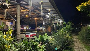 An outdoor seating area with tables and chairs, surrounded by greenery and hanging plants. - Moonshine Resort Chumphon (Chumphon)