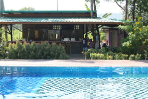 A swimming pool with a tiled edge, a covered area with a counter, and greenery around. - Moonshine Resort Chumphon (Chumphon)