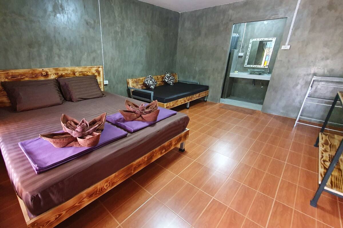 Una habitación con cama, una mesita y un espejo.