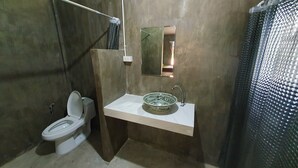 A bathroom with a toilet, a sink with a mirror, and a shower curtain. - Moonshine Resort Chumphon (Chumphon)