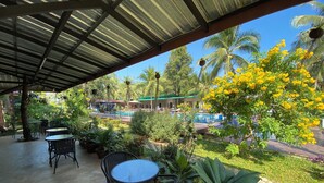 A covered outdoor area with tables and chairs, a pool, and lush greenery. - Moonshine Resort Chumphon (Chumphon)