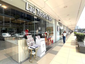 Ein Schaufenster mit einem Schild, auf dem 'Lau Tasteful Eats' steht, und einer Speisenauslage vor der Tür.