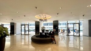 Een ruime lobby met een centraal zitgedeelte, grote ramen en een modern plafondontwerp.