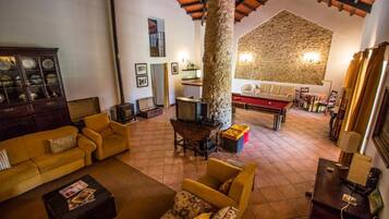 A cozy living room with a fireplace, yellow sofas, a wooden cabinet, and a stone wall.
