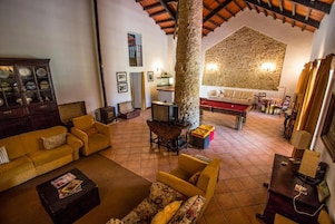 A cozy living room with a fireplace, yellow sofas, a wooden cabinet, and a stone wall.