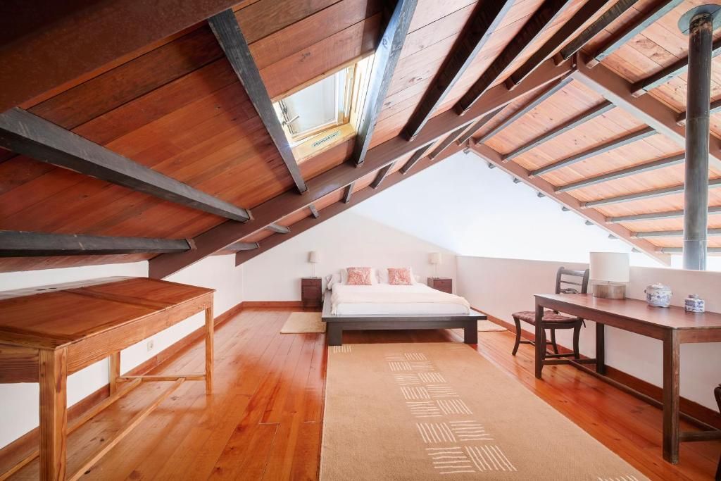 A bedroom with a sloped ceiling, a bed, a desk, and a chair.
