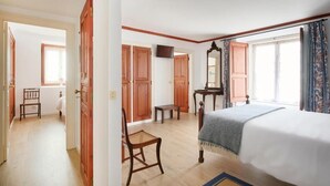 Une chambre à coucher comprenant un lit, une armoire en bois, une petite table, une chaise et un téléviseur.