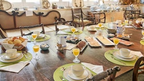 Une table à manger dressée avec des aliments pour le petit-déjeuner, notamment des viennoiseries, du pain et des boissons.