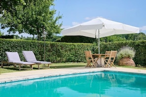 A swimming pool with lounge chairs and a table with an umbrella. - Quinta Da Alcaidaria-mór (Ourem)