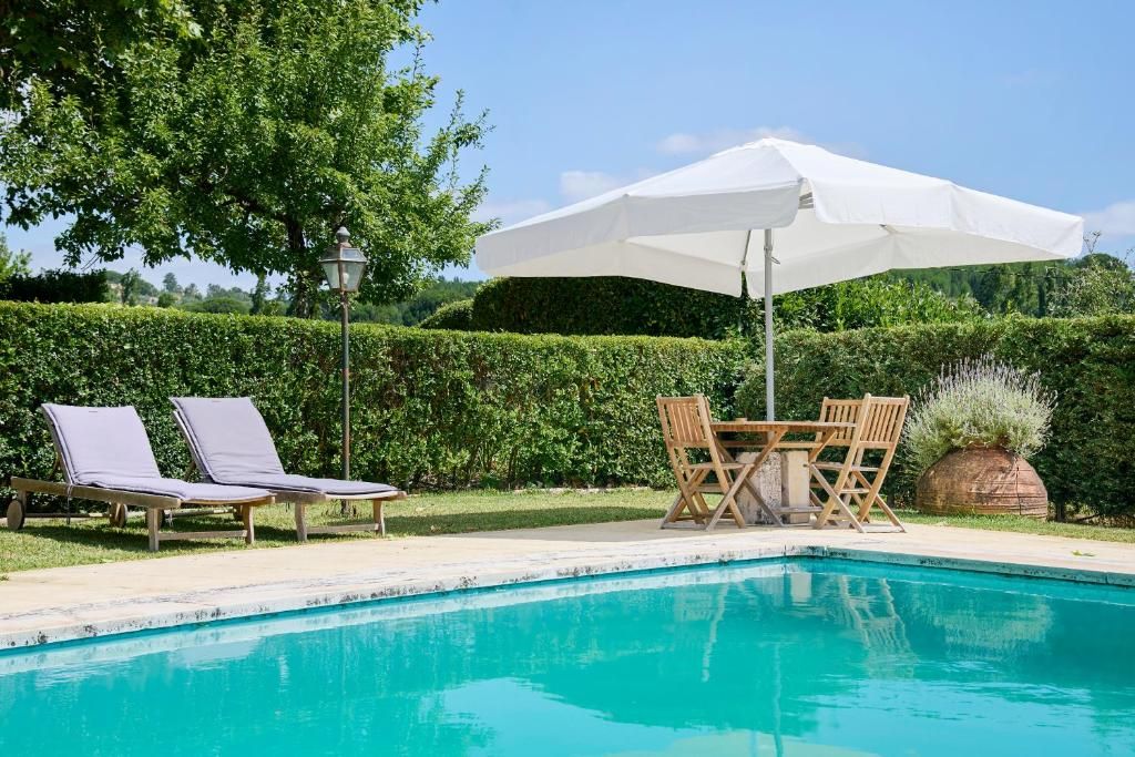A swimming pool with lounge chairs and a table with an umbrella.
