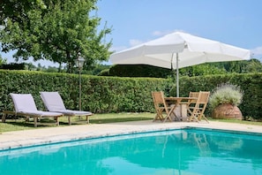 A swimming pool with lounge chairs and a table with an umbrella. - Quinta Da Alcaidaria-mór (Ourem)