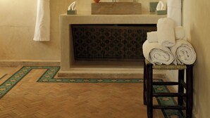 A bathroom with a sink, mirror, towel rack, and a small table with towels. - Jenan Mayshad (Marrakech)