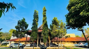 A building with a tiled roof, surrounded by trees and parked cars.