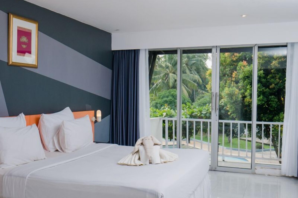 A hotel room with a large bed, a view of the outdoors, and a balcony.