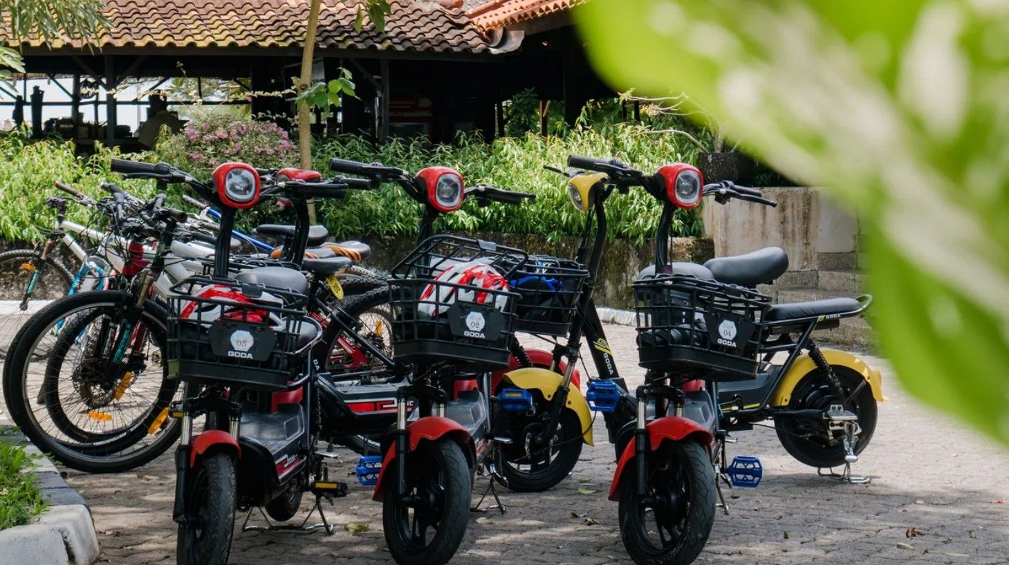 A row of stationary motorcycles parked outdoors, with a building in the background.