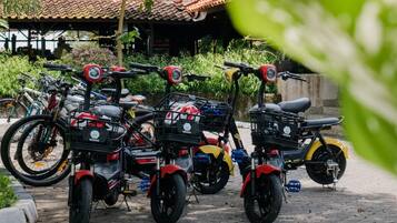A row of stationary motorcycles parked outdoors, with a building in the background.