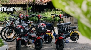 A row of stationary motorcycles parked outdoors, with a building in the background.
