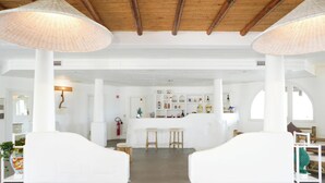 A spacious room with white furniture, a central bar area, and a high wooden ceiling. - Hotiday Vulcano Porto  (Lipari)