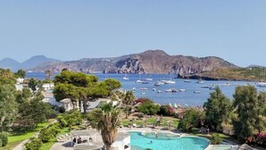 A coastal resort with a swimming pool, lush greenery, and boats in the background. - Hotiday Vulcano Porto  (Lipari)
