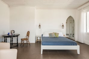 A bedroom with a bed, a chair, a small table with a kettle, and a lamp. - Hotiday Vulcano Porto  (Lipari)