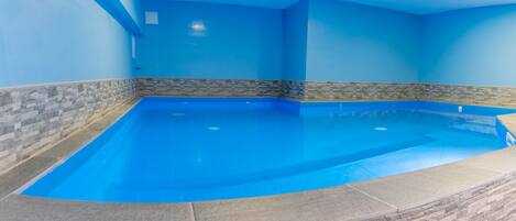 An indoor swimming pool with blue walls and stone accents.