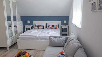 A bedroom with a bed, a bedside table, a wardrobe, a sofa, and a fruit bowl.