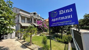 Un immeuble portant l’inscription « Dina Apartmanı » et offrant des équipements tels qu’une piscine intérieure, une connexion Wi-Fi gratuite et une borne de recharge pour véhicules électriques.