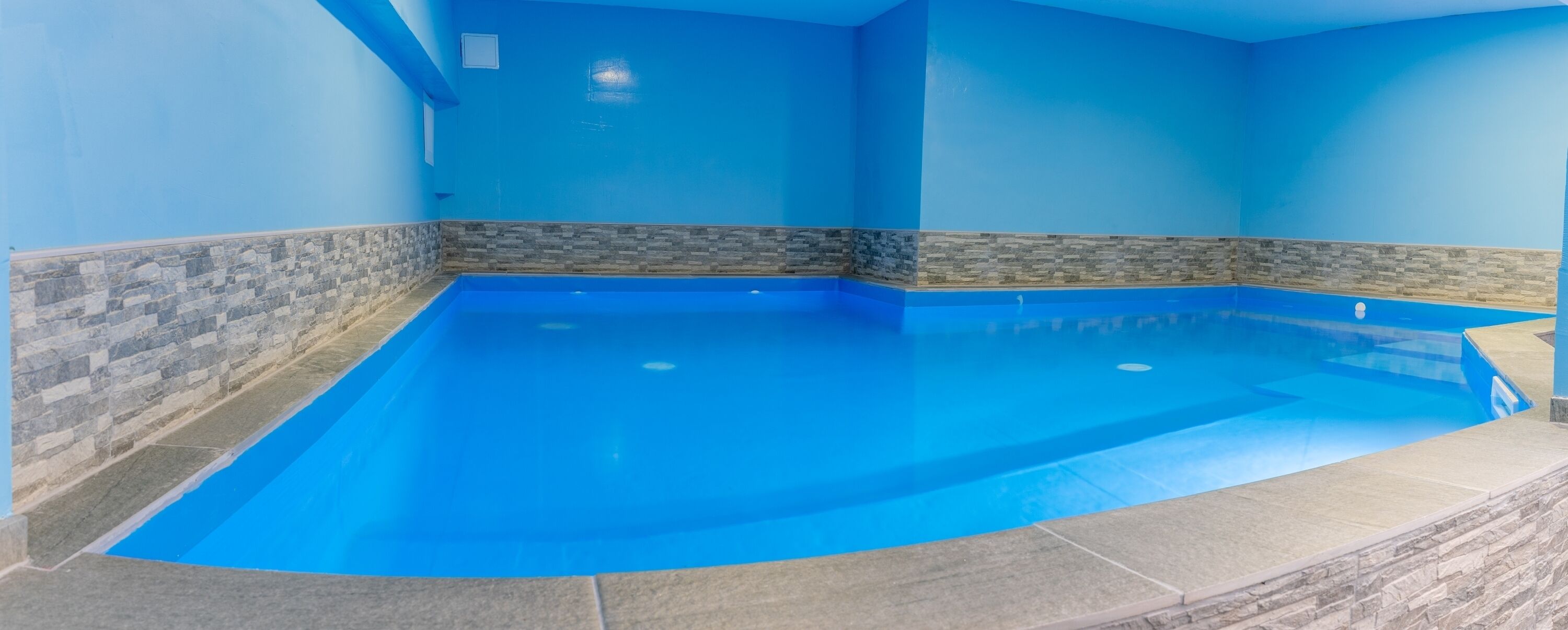An indoor swimming pool with blue walls and stone accents.