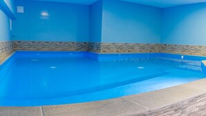 Una piscina interior con paredes azules y detalles de piedra.