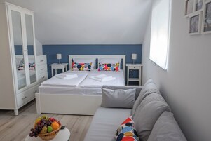 Un dormitorio con cama, mesita de noche, armario, sofá y frutero.