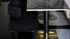 Ein modernes Interieur mit schwarzen und goldenen Tischen, dunkel gepolsterten Sesseln und einem minimalistischen Design.