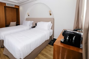 A hotel room with two beds, a wooden desk with a coffee maker, and a phone on the nightstand. - Chic Hotel (Rabat)