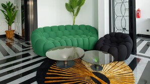 Eine moderne Lobby mit einem grünen Sofa, einem schwarzen Sitzsack, einem Glastisch und einem gemusterten Teppich.