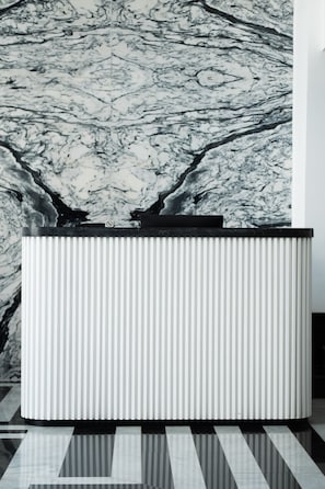 A modern reception desk with a marble wall background. - Chic Hotel (Rabat)