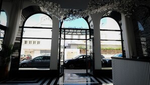 Ein Hotel Eingang mit Glastür, Fliesenboden und Blick auf parkende Autos.
